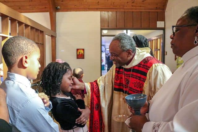 Pastor at St. Ambrose blessing children.
