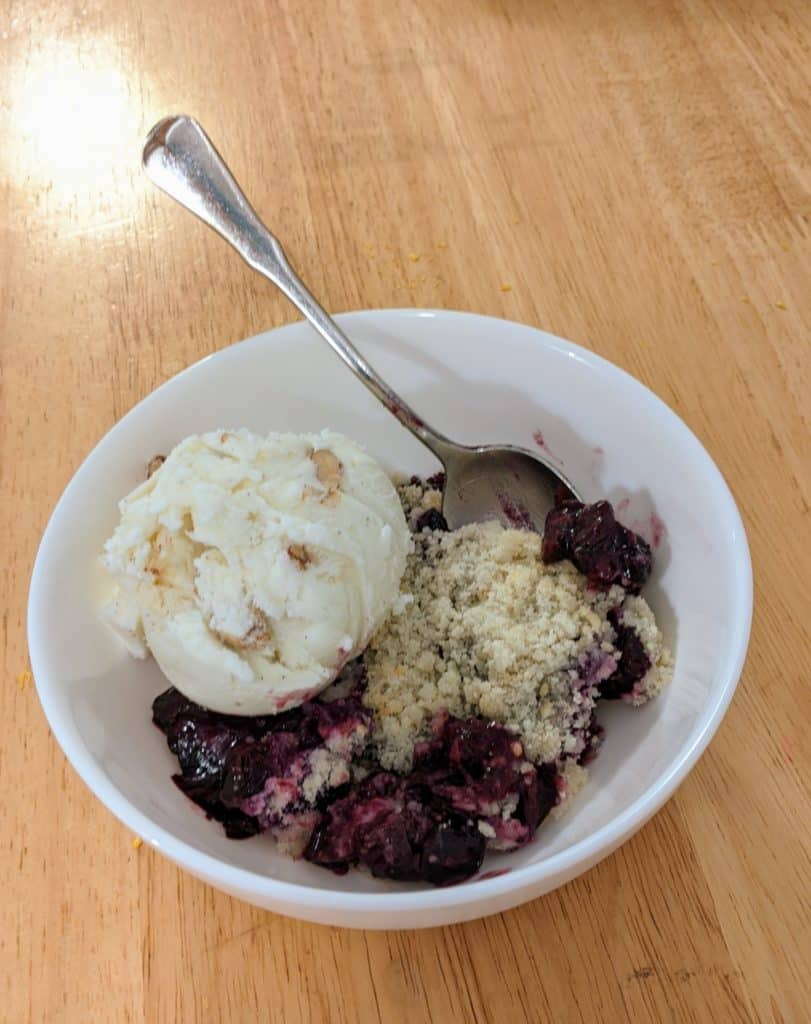 A bowl with Blueberry Crisp and a scoop of ice cream.