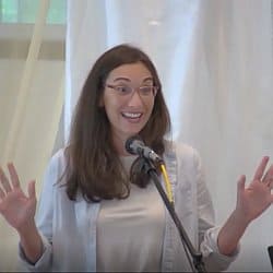 Melissa preaching with arms outstretched and a big smile.