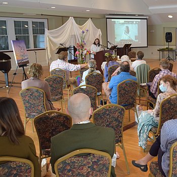 Congregation facing forward, while Melissa preaches, Zoom screen in the background. Easter Sunday, 2022