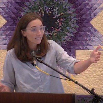 Melissa preaching at RMC with one hand outstretched.