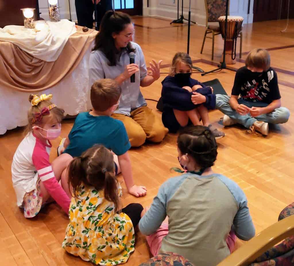Melissa talking with kids while sitting on the floor during an RMC church service.