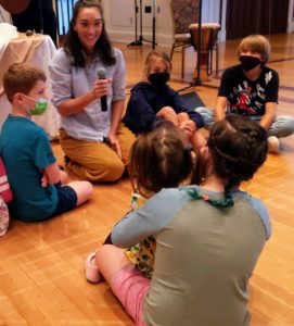Melissa talking with kids while sitting on the floor during an RMC church service.