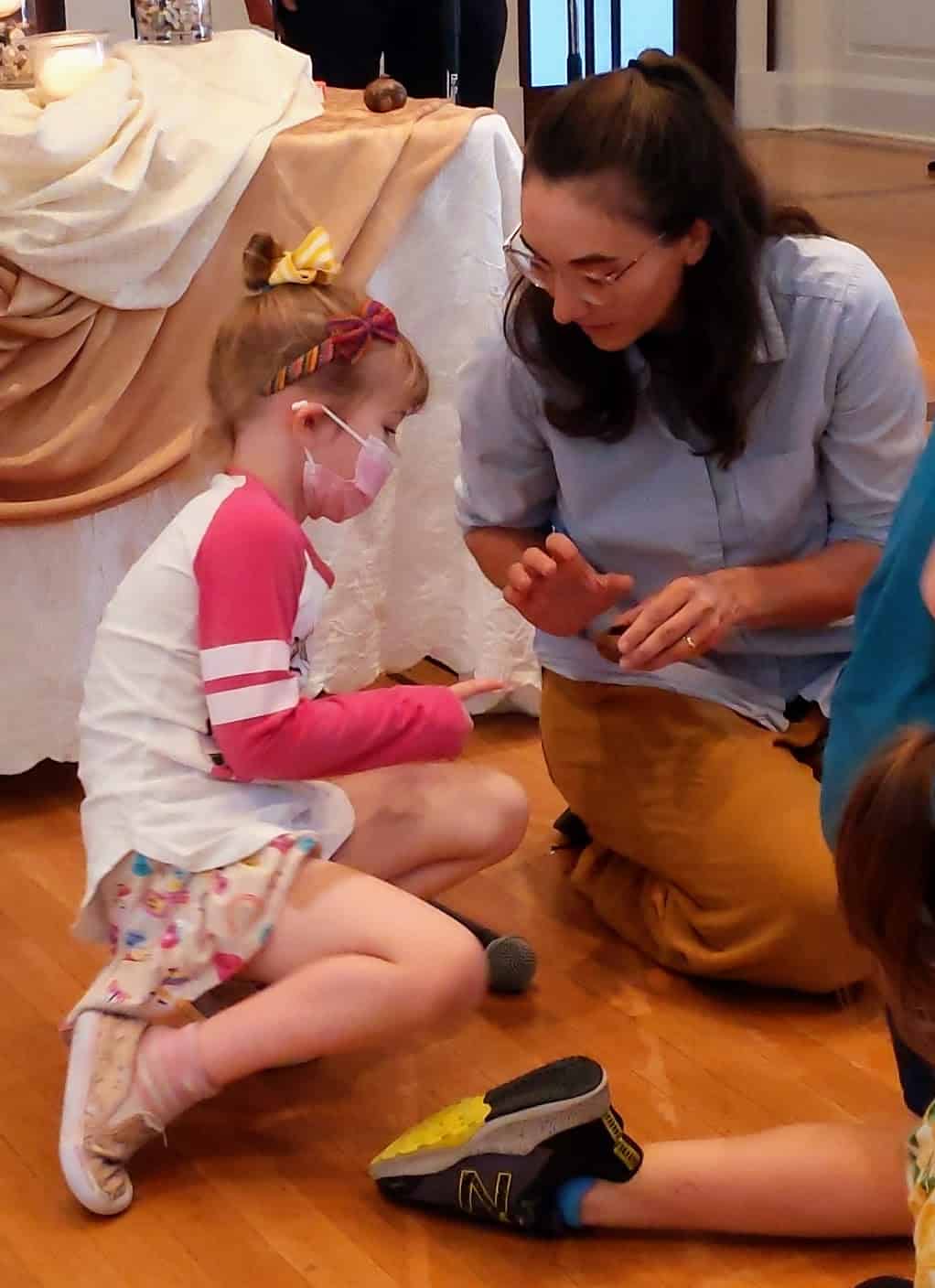 Melissa using oil to make the sign of the cross on a child's hand during children's time at RMC. 