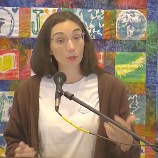 Melissa preaching in front of a colorful quilted wall hanging.