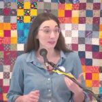 Raleigh Mennonite Church Melissa preaching in front of a colorful quilted background.