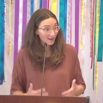 Melissa preaching in front of a ribbon banner.