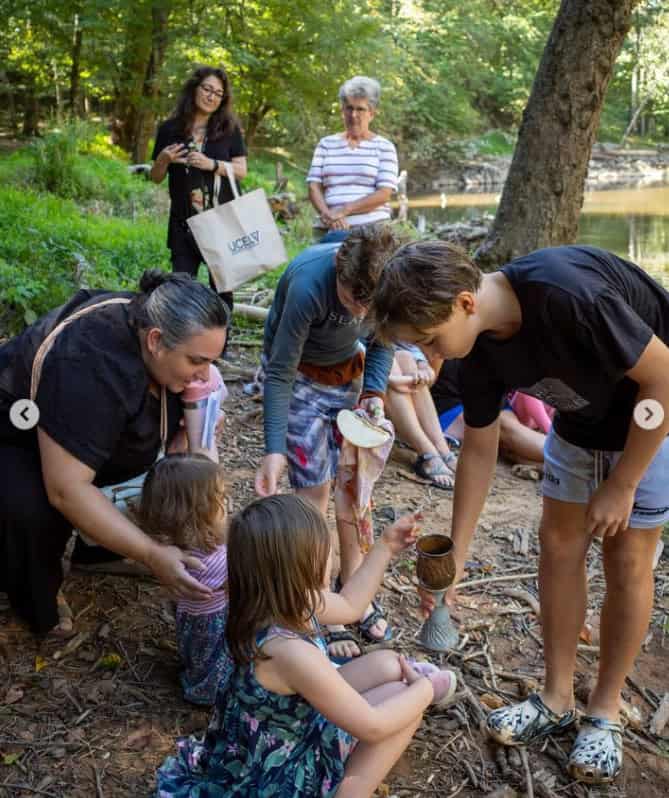 Two boys serving communion to two young children while their mother watches.