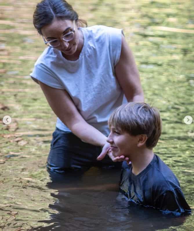 Pastor Melissa holding young person bein the river during baptism.