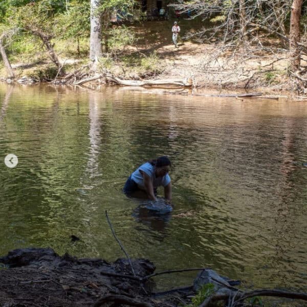Pastor Melissa in the Eno River with her son, baptizing him.