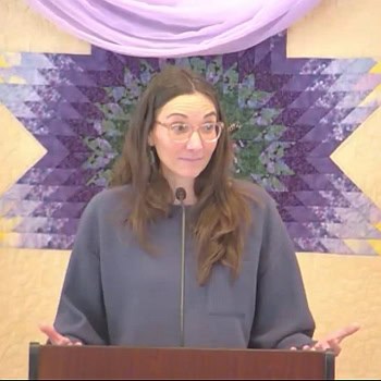 Melissa preaching on Jan. 12, 2025 in front of a purple and yellow quilted banner.