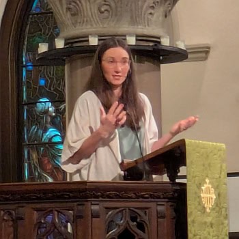 Melissa preaching in the sanctuary at Church of the Good Shepherd. She stands in the podium with her hands in front of her with a marble pillar seen in the background.