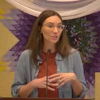 Melissa preaching at RMC in front of a quilted banner on May 4, 2025.