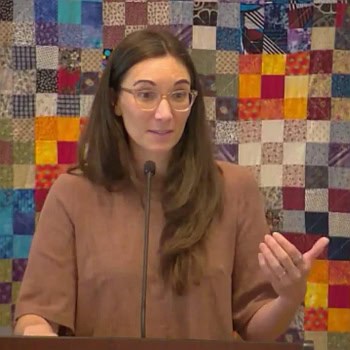 Melissa preaching at RMC on May 25, 2025, with one hand extended.