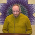 Phil preaching on Jan. 11, 2026 in front of a yellow and purple quilted wall hanging.